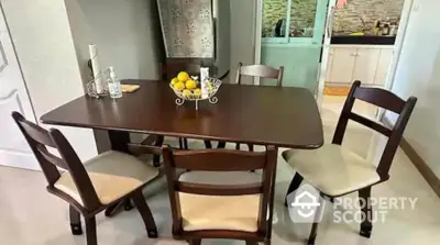 Charming dining area with elegant wooden table and chairs, adjacent to a modern kitchen.