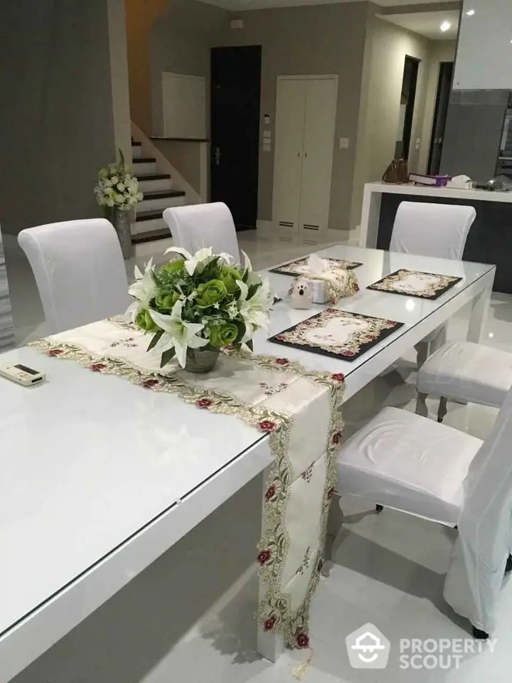 Elegant dining area with white table and chairs, floral centerpiece, and modern decor.