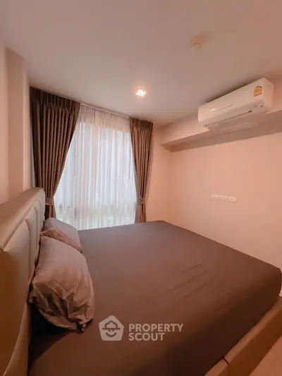 Cozy bedroom with modern air conditioning and large window with curtains.