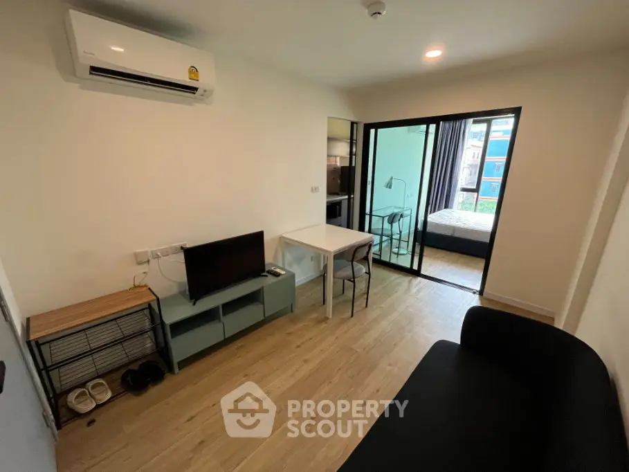 Modern apartment living room with sleek furniture and open view to bedroom