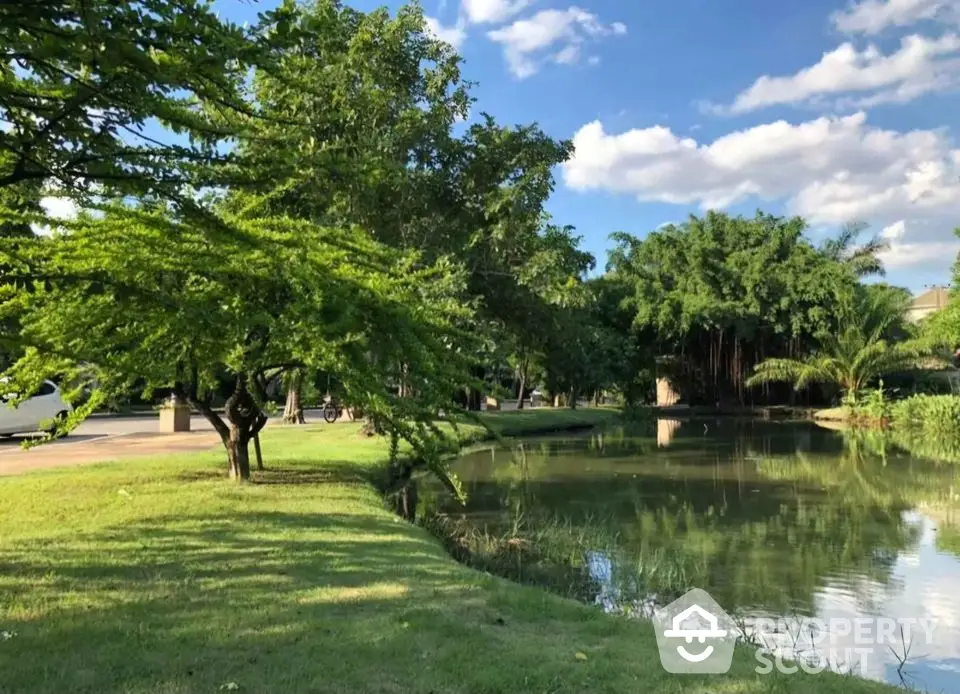 Serene garden view with lush greenery and tranquil pond under blue skies.