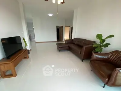 Spacious living room with modern leather furniture and flat-screen TV.