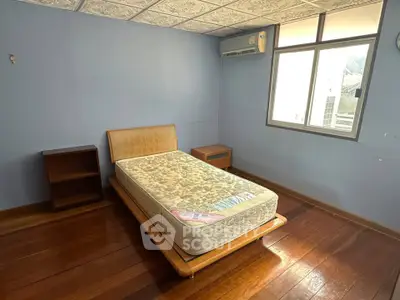 Spacious bedroom with wooden flooring and natural light