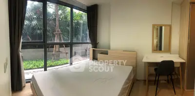 Spacious bedroom with large windows and garden view, featuring modern furniture and natural light.