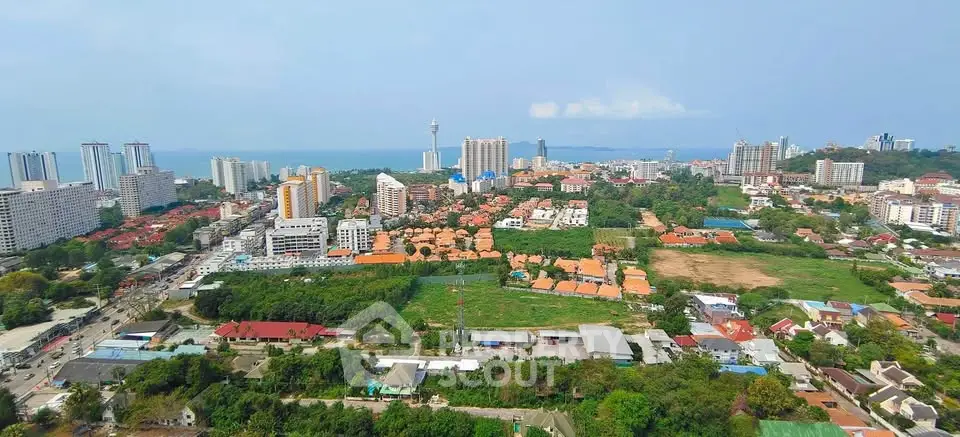 Stunning aerial view of vibrant cityscape with lush greenery and ocean backdrop, ideal for real estate investment.