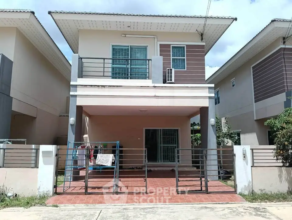 Modern two-story house with balcony and gated entrance in a suburban neighborhood.