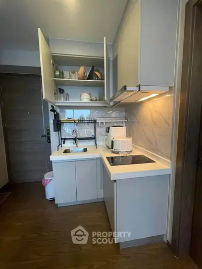 Modern compact kitchen with sleek cabinetry and integrated appliances in a stylish apartment.