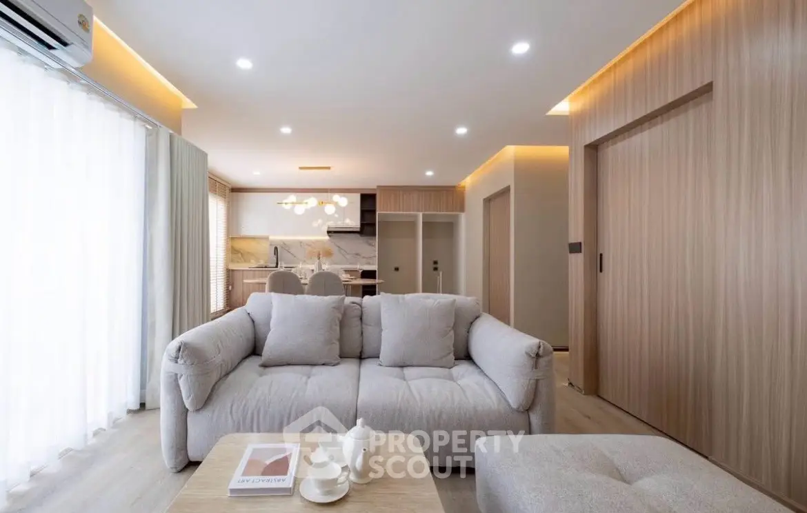 Modern living room with cozy sofa and open kitchen layout in stylish apartment.