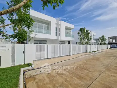 Modern white two-story house with large windows and gated driveway