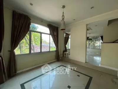 Spacious living room with large windows and elegant curtains, offering abundant natural light and garden view.