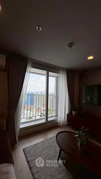 Stylish living room with balcony offering stunning city view, modern decor, and natural light.