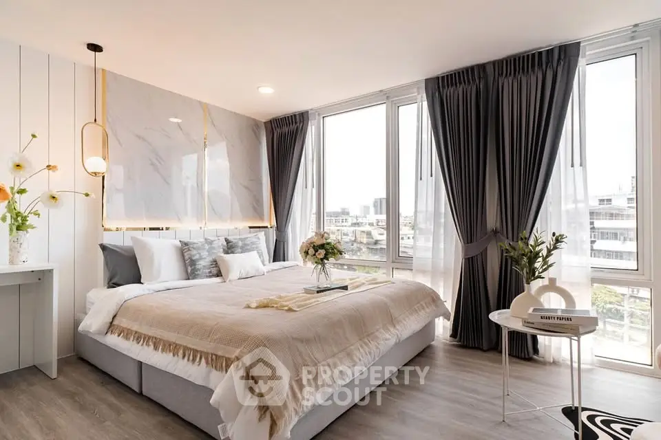 Luxurious bedroom with large windows and elegant decor, offering a bright and inviting atmosphere.