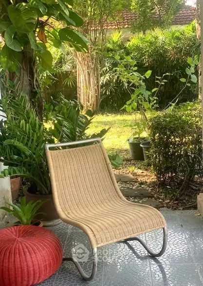 Charming garden patio with a cozy wicker chair and lush greenery, perfect for relaxation.