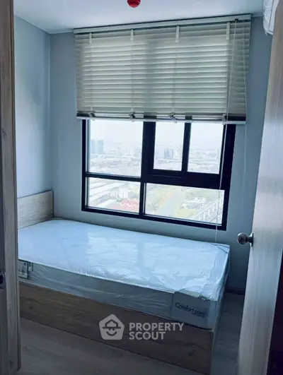 Cozy bedroom with city view, featuring a single bed and large window for natural light.