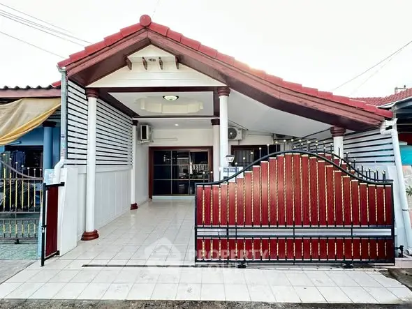 Charming single-story house with a red-tiled roof and gated entrance.