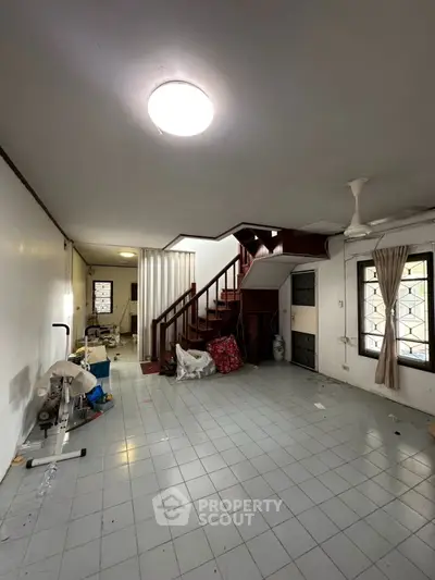 Spacious interior with staircase and tiled floor, ideal for renovation.