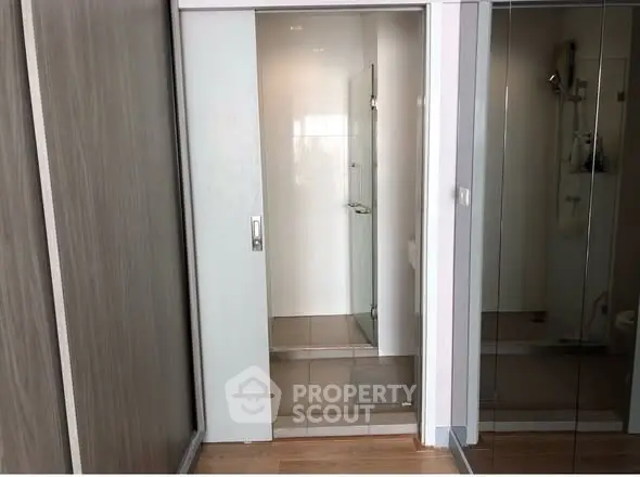 Modern bathroom with sliding door and mirrored closet in sleek apartment.