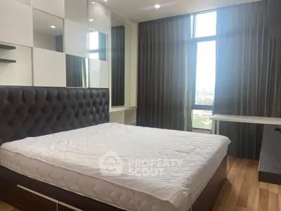 Modern bedroom with large window and stylish decor in a contemporary apartment.