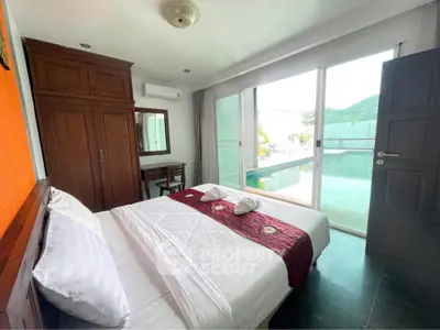Spacious bedroom with pool view and elegant wooden furniture, perfect for relaxation and comfort.