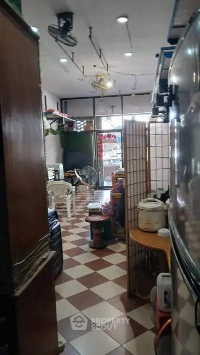 Cozy interior with checkered flooring and eclectic decor, featuring a compact living space and kitchen area.