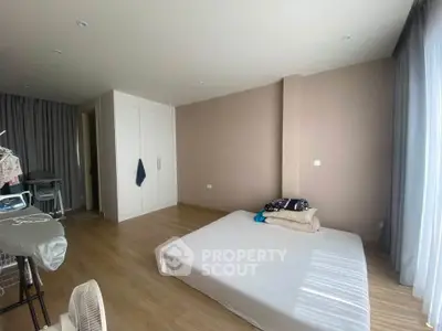 Spacious bedroom with minimalist decor and large window for natural light