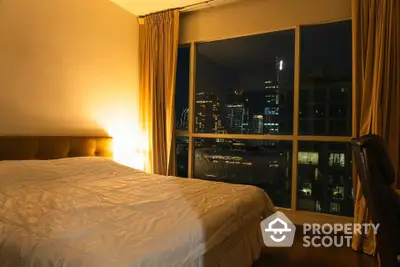 Luxurious bedroom with stunning city view at night, featuring elegant curtains and cozy lighting.