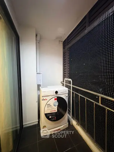 Compact balcony with washing machine and railing, ideal for urban living.