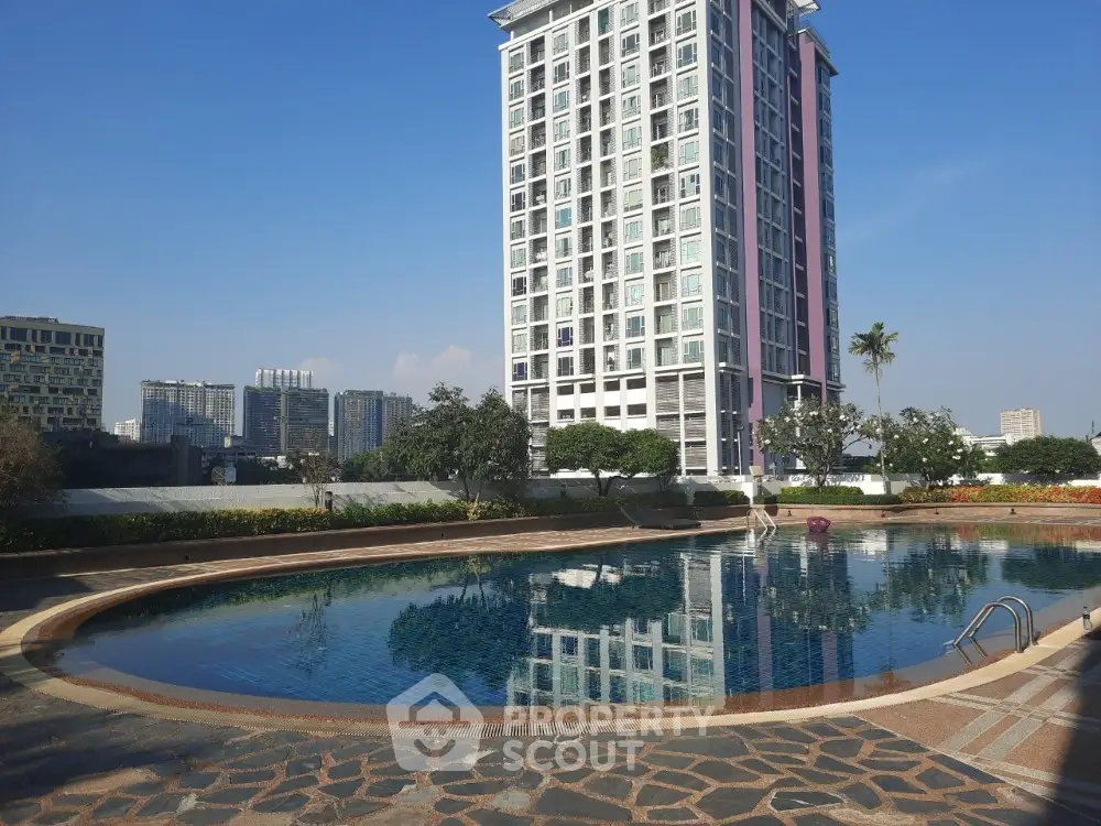 Luxurious high-rise condominium with a stunning reflective pool set amidst a lush garden, offering a tranquil urban oasis with a modern architectural backdrop.