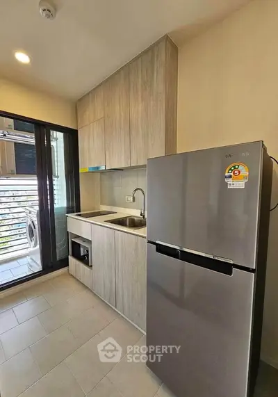 Modern kitchen with sleek cabinetry and stainless steel fridge in a compact apartment setting.