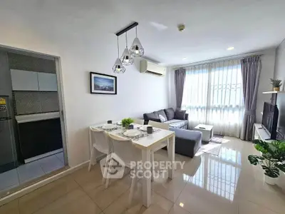 Modern living room with dining area and natural light, featuring stylish decor and open layout.