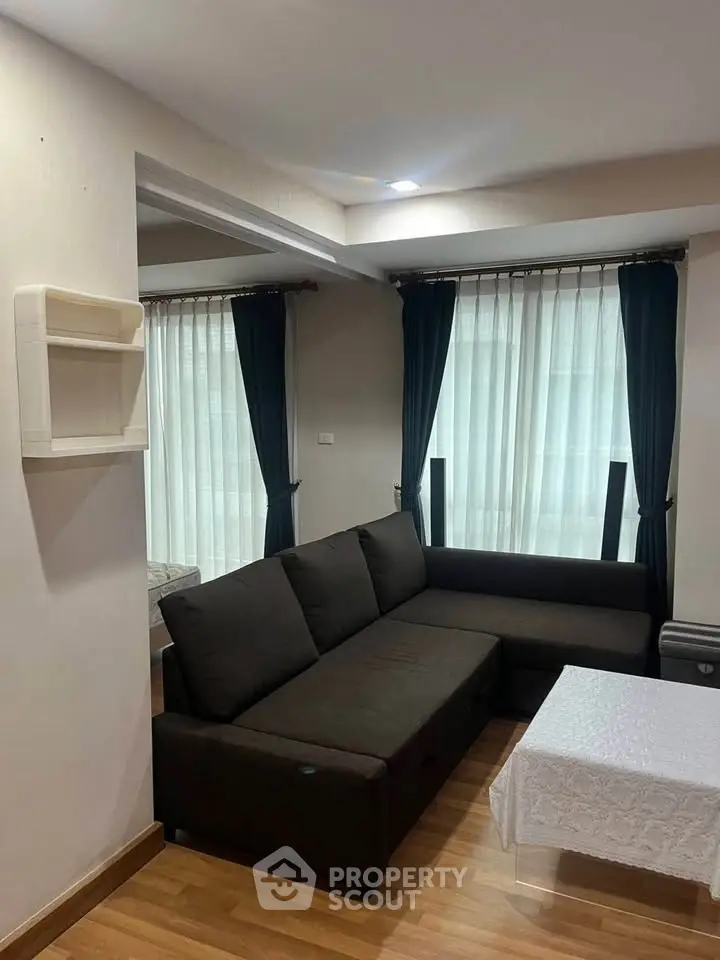 Cozy living room with dark sofa and elegant curtains, perfect for relaxation.