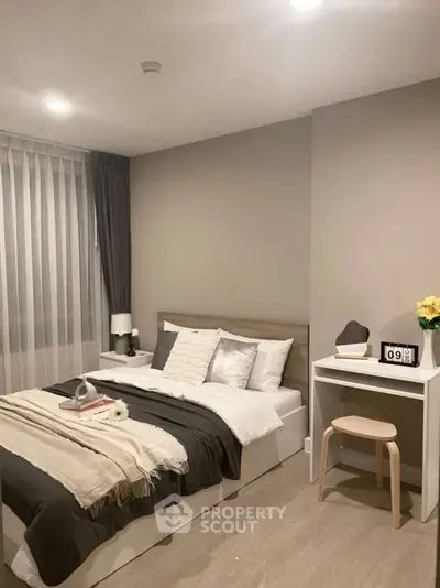 Modern bedroom with cozy decor and natural light, featuring a stylish bed and compact study area.