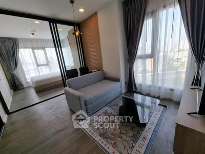 Modern living room with large windows and city view, featuring a cozy sofa and stylish decor.