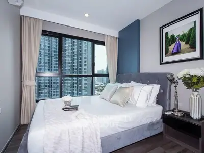 Modern bedroom with large window and city view in a stylish apartment.