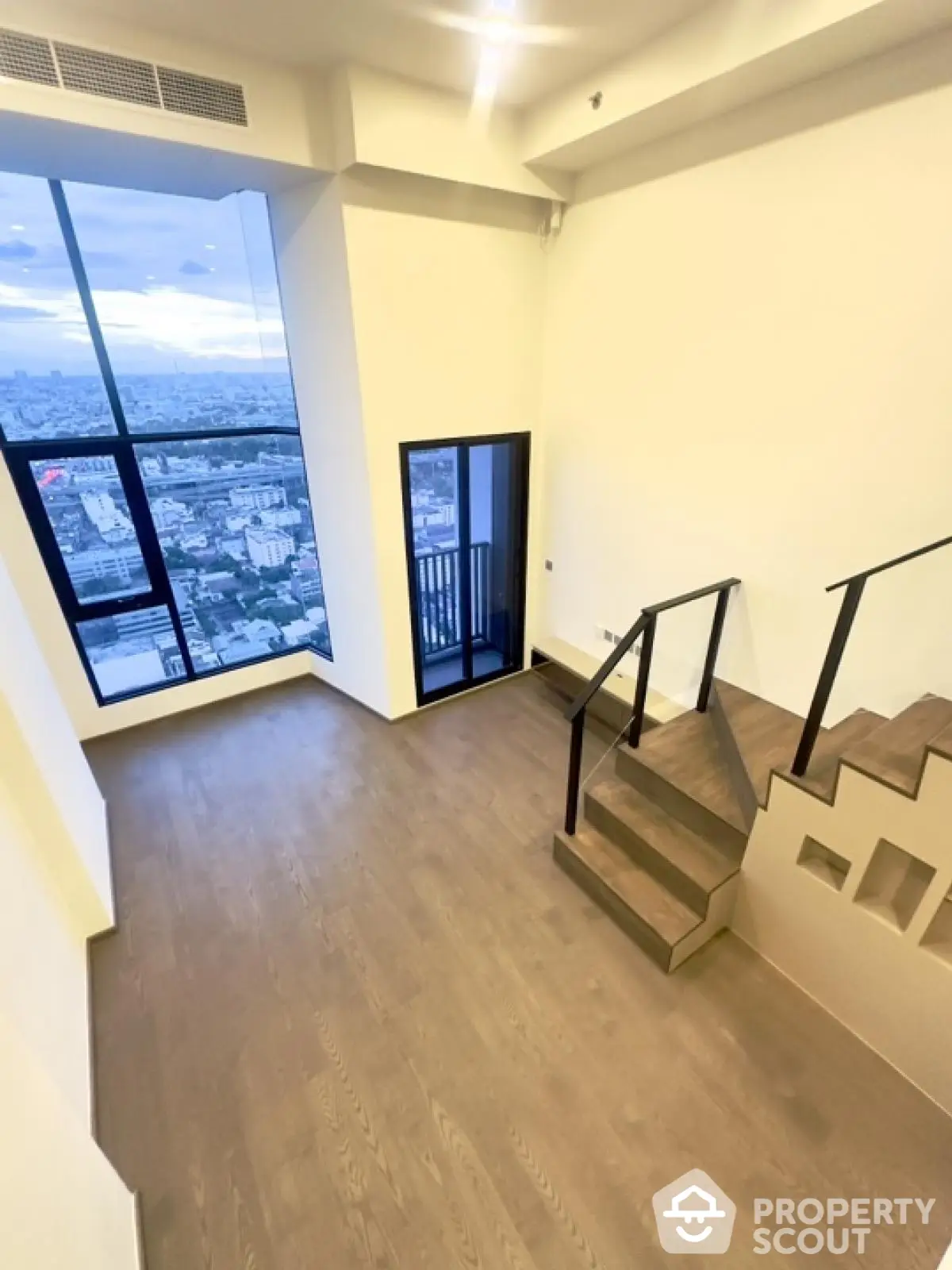 Stunning high-rise apartment with floor-to-ceiling windows offering breathtaking city views and modern staircase.