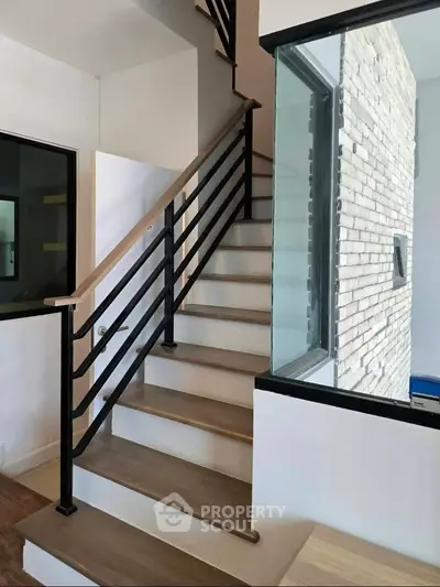 Modern staircase with sleek metal railing and wooden steps in a contemporary home interior.