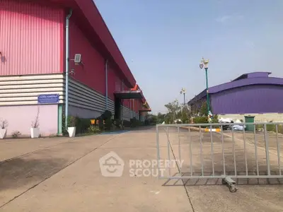 Spacious industrial warehouse exterior with vibrant colors and secure gated entrance.