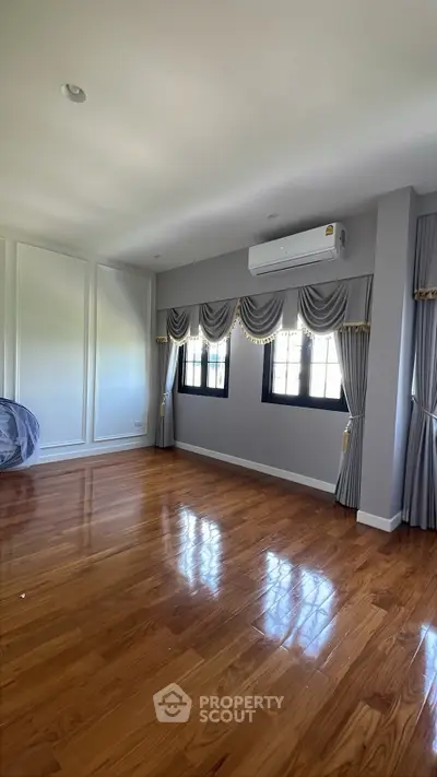 Spacious empty room with polished wooden floors and elegant drapery, perfect for customization.