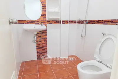 Modern bathroom with stylish red tile accents and sleek fixtures.