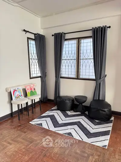 Cozy corner with stylish rug and seating in a bright room with large windows.