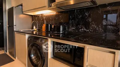 Modern kitchen with sleek black marble backsplash and built-in appliances, including washing machine and oven.