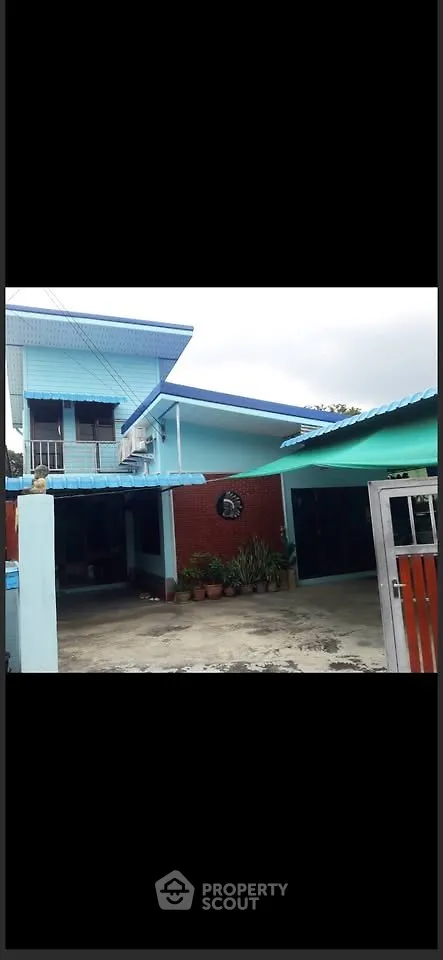Charming two-story blue house with spacious driveway and lush garden.