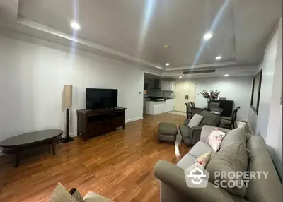 Spacious living room with gleaming hardwood floors, modern lighting, and an open kitchen layout, perfect for entertaining and comfortable living.