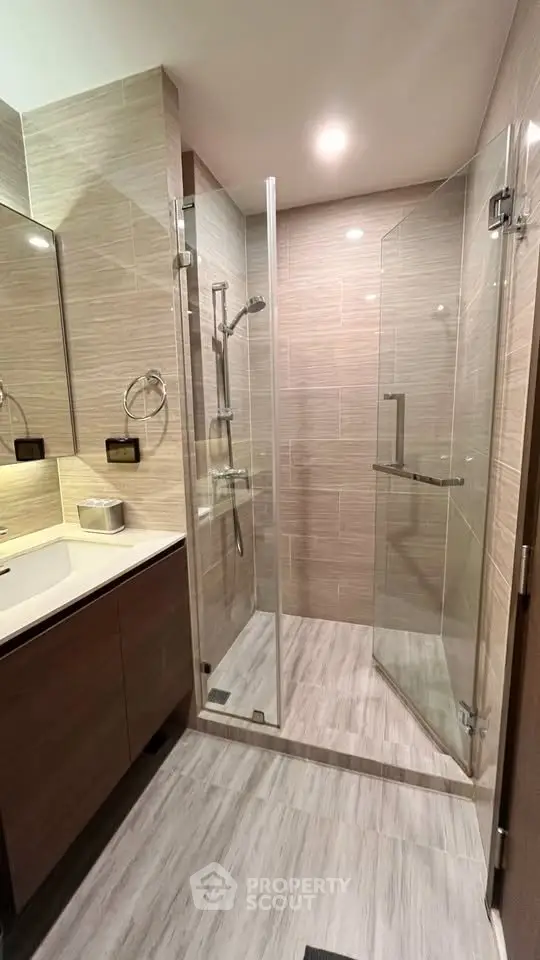 Modern bathroom with glass shower enclosure and sleek vanity in contemporary apartment.