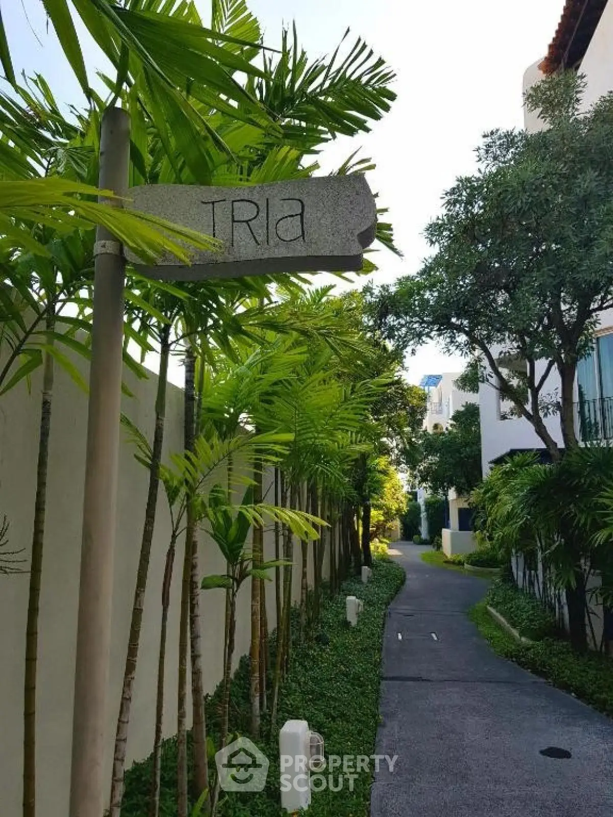 Charming garden pathway at Tria residential complex with lush greenery and modern architecture.