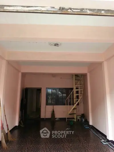 Spacious interior with spiral staircase and terrazzo flooring, ideal for creative renovation.