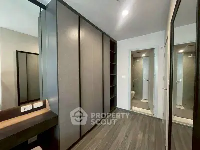Modern bedroom with sleek wardrobe and en-suite bathroom, featuring elegant design and ample storage space.