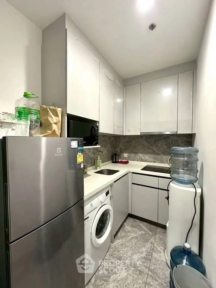 Modern compact kitchen with sleek cabinetry and built-in appliances in a stylish apartment.