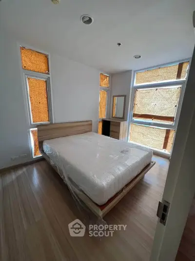Spacious bedroom with large windows and modern wooden flooring, perfect for natural light lovers.