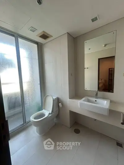 Modern bathroom with sleek fixtures and large frosted glass window